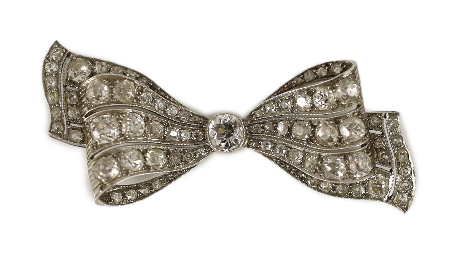 An early to mid 20th century white gold and graduated diamond cluster millegrain set ribbon bow brooch